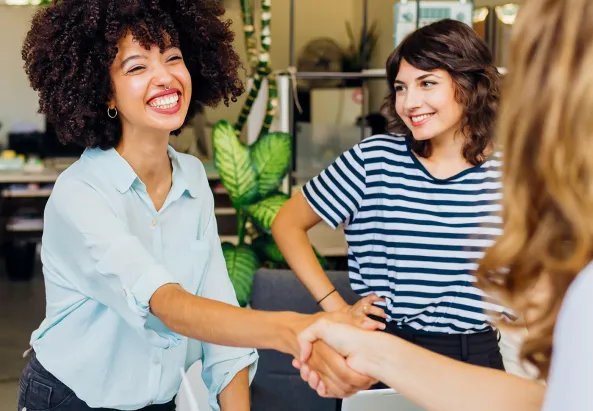 Une femme tout sourire, nouvellement adhérente Harmonie Mutuelle ESS, serre la main d'une autre femme que l'on voit de dos, qui est sa nouvelle conseillère Harmonie Mutuelle ESS. Une troisième femme se tient à côté de la première et sourit, il s'agit d'une adhérente Harmonie Mutuelle ESS qui a parlé à la première des avantages de rejoindre Harmonie Mutuelle ESS et qui l'a convaincue. Cette image illustre les avis et témoignages fait par nos adhérentes et adhérents.